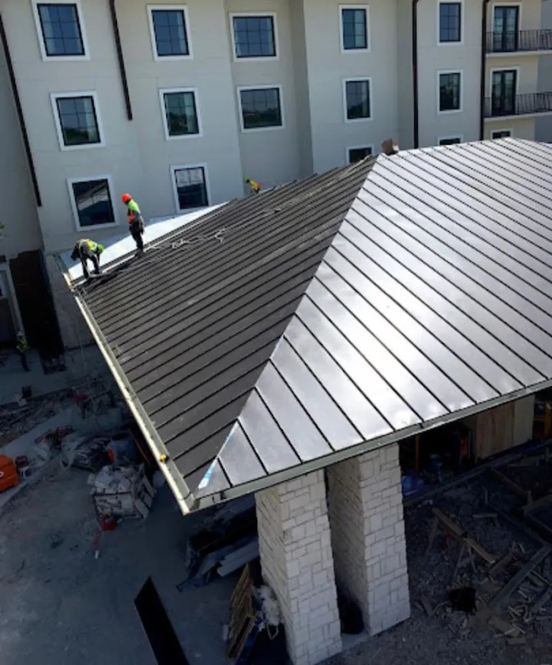 Crew installing standing seam metal roof panels on a commercial project in Reynolds